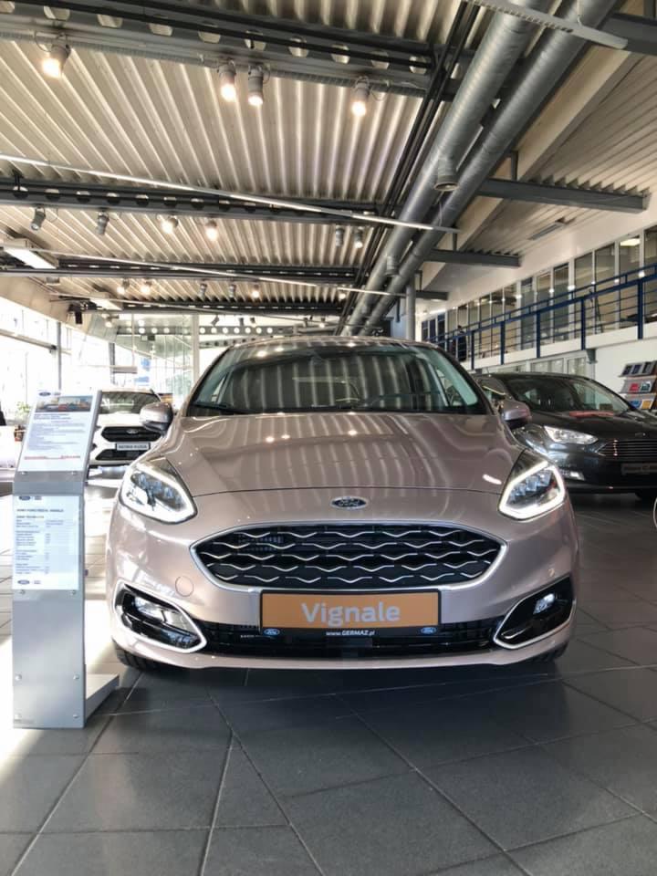 Szampański Ford Fiesta Vignale w salonie samochodowym, widok z przodu, oświetlenie halogenowe na suficie.