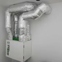 Centrala wentylacyjna WANAS 415 Hi-Tech z izolowanymi przewodami wentylacyjnymi w pomieszczeniu o białych ścianach.