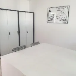 Jasne biuro z białym stołem, krzesłami w pepitkę, szafą na dokumenty i grafiką przedstawiającą spadek produktywności.