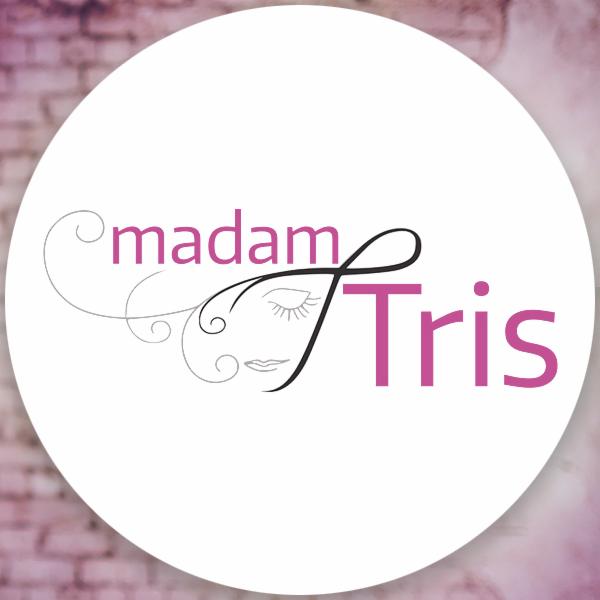 Logo firmy 'Madam Tris' z minimalistycznym rysunkiem twarzy i fioletowym napisem na białym okręgu z rozmytym ceglanym tłem.