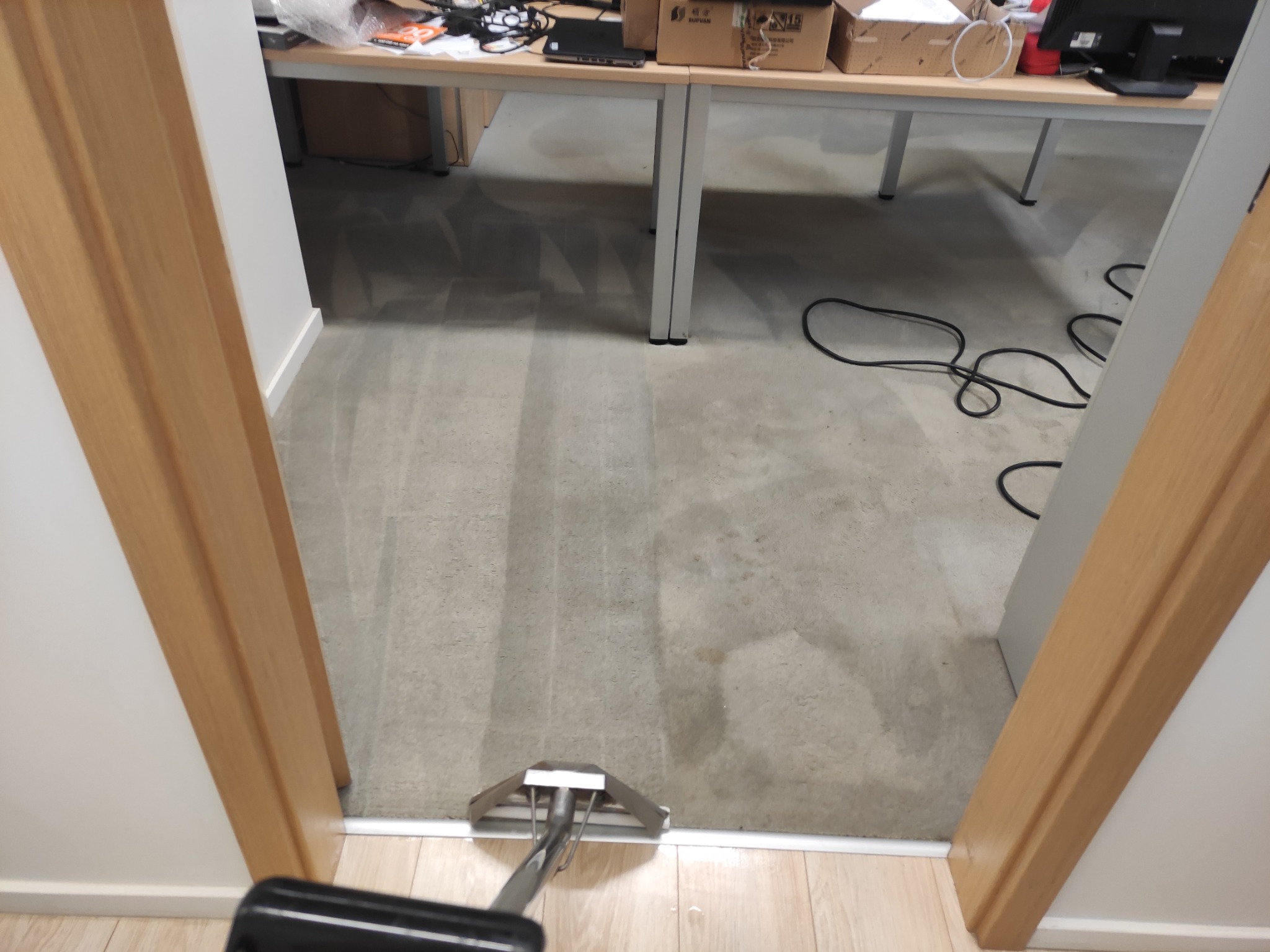 Dywan w biurze czyszczony profesjonalnym odkurzaczem piorącym, widoczne ślady po czyszczeniu.