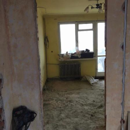 Michał Baska - Pokój w trakcie demontażu, widoczne gołe ściany, gruz na podłodze i wiszący młot pneumatyczny, przygotowanie do remontu.