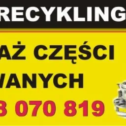 Żółty baner reklamowy z napisem 'METAL RECYKLING LUTY', 'SPRZEDAŻ CZĘŚCI UŻYWANYCH' oraz numerem telefonu, obok widoczne różne części samochodowe.