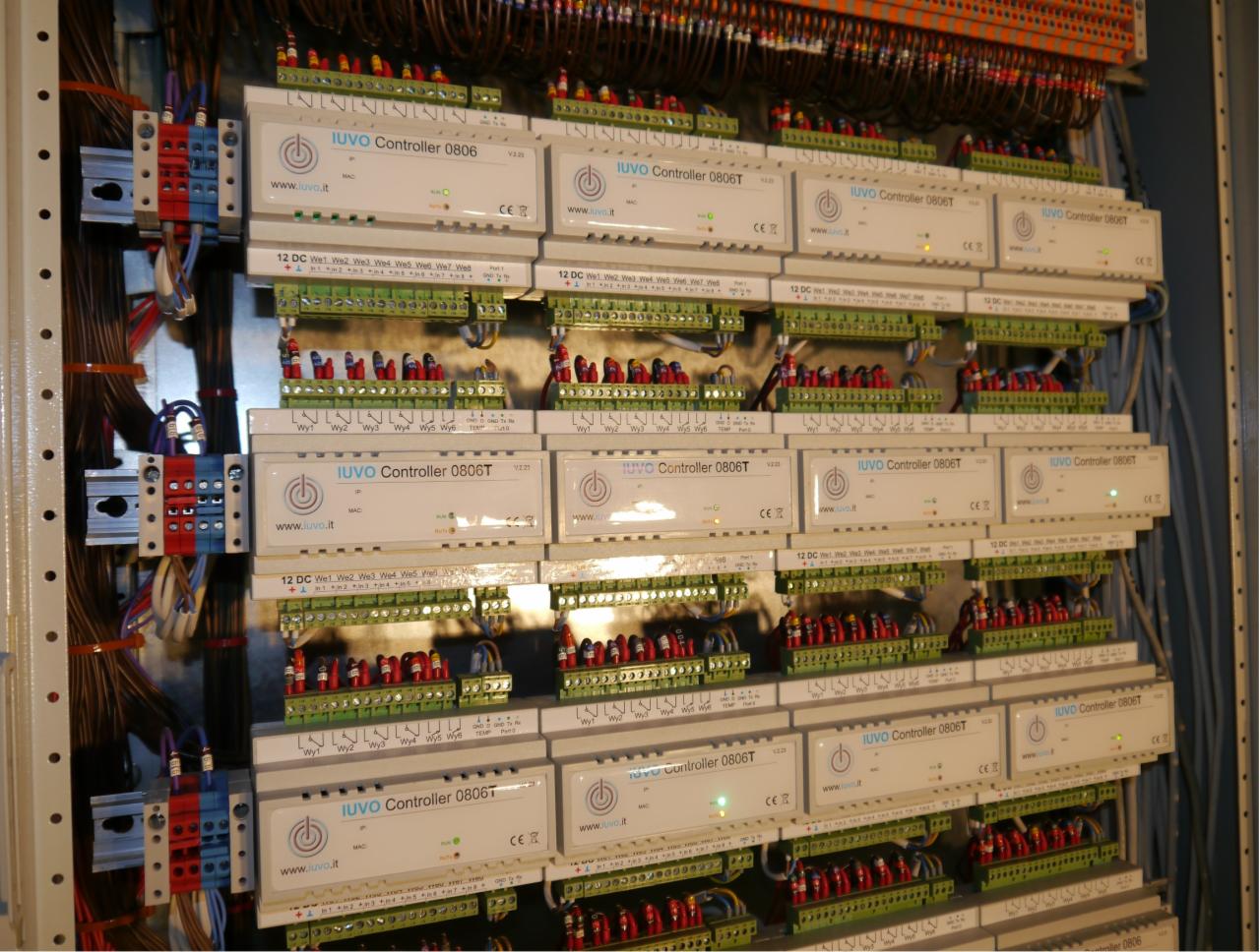 Rozbudowana szafa sterownicza z wieloma modułami IUVO Controller 0806T, licznymi złączkami i okablowaniem, widoczne diody LED sygnalizujące pracę urządzeń.