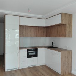 SCHAFFERMAN - szafy na wymiar - Nowoczesna, narożna kuchnia z białymi, lakierowanymi frontami i okładzinami w kolorze dębu amerykańskiego, wyposażona w płytę indukcyjną i piekarnik marki Bosch.