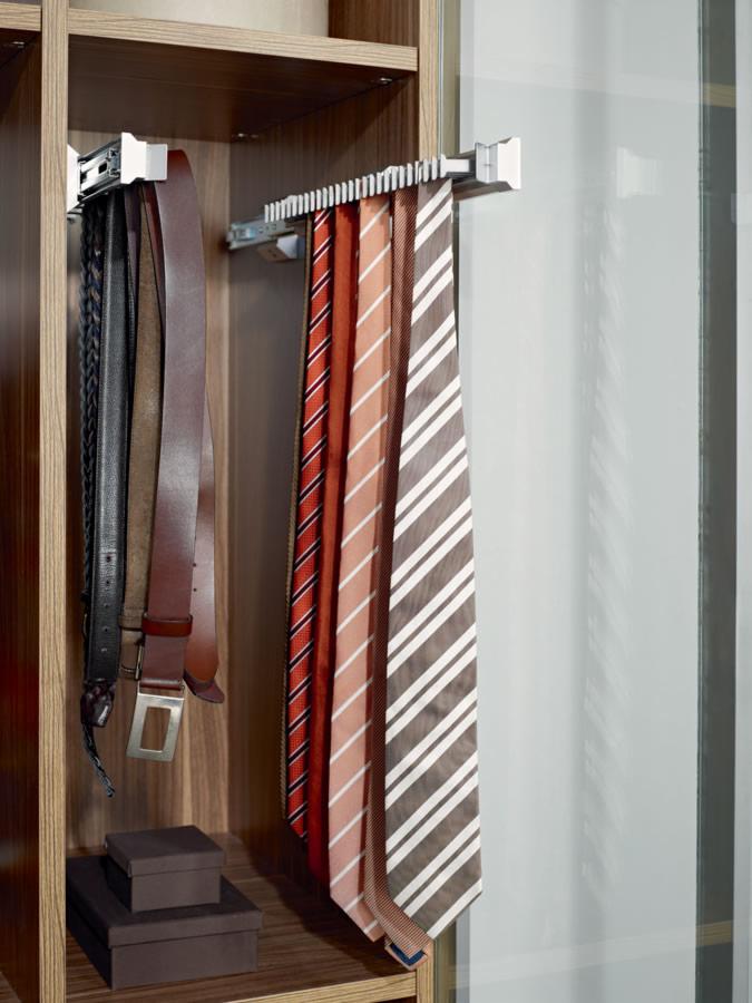 Wysuwany wieszak na paski i krawaty w szafie wnękowej z drewnianymi półkami i szklanymi drzwiami.