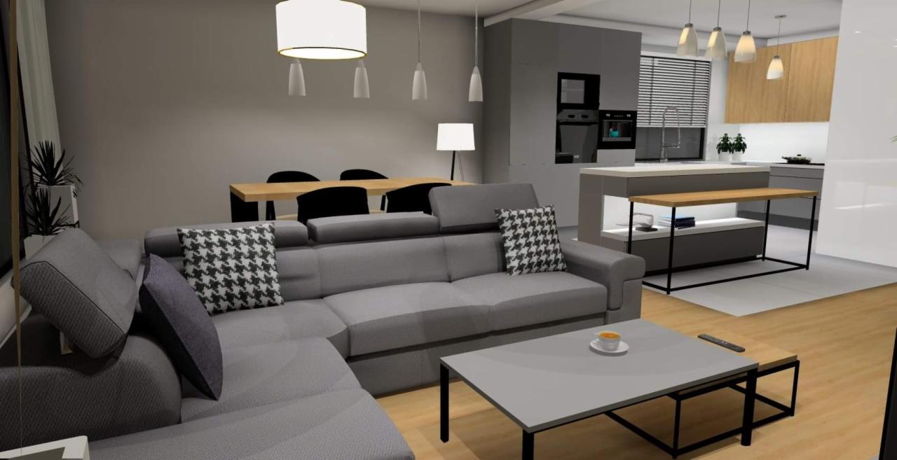 Wizualizacja przestronnego, nowoczesnego wnętrza z szarym narożnikiem, otwartą kuchnią i jadalnią, oświetlonego wiszącymi lampami.