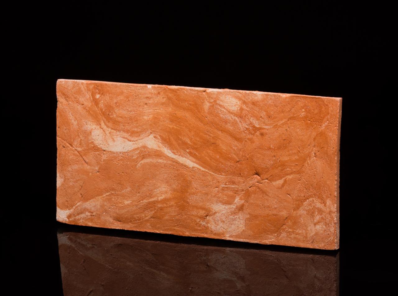 Płytka podłogowa imitująca terakotę z marmurkowym wzorem na czarnym, błyszczącym tle.