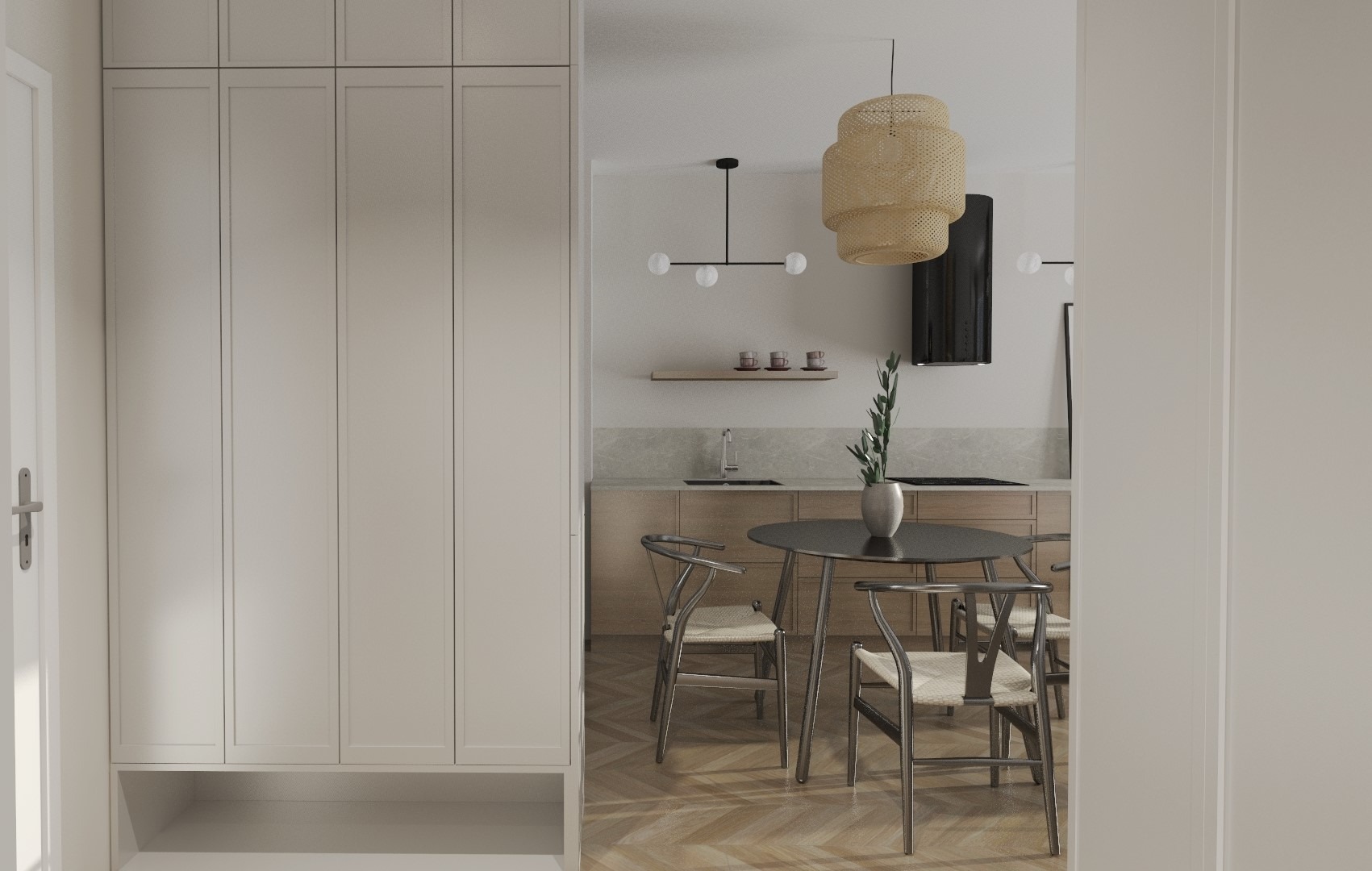 Jasne wnętrze mieszkania z parkietem w jodełkę, widok na kuchnię z okrągłym stołem, krzesła z wiklinowym siedziskiem oraz zabudowa szaf w przedpokoju.
