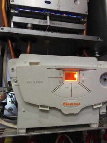 Wnętrze kotła gazowego Immergas EOLO STAR z widocznym płomieniem palnika i panelem sterowania z podświetlonym wyświetlaczem.