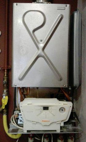 Zamontowany, używany gazowy kocioł kondensacyjny marki Immergas, widoczne rury, zawór gazowy z żółtą etykietą i panel sterowania.