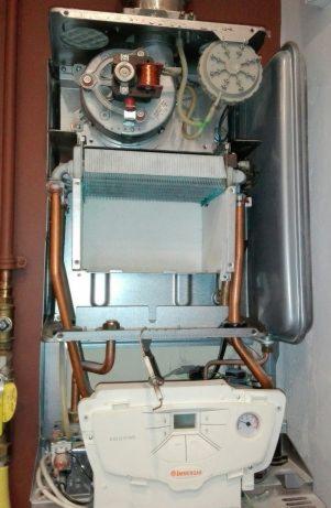 Otwarty, srebrny kocioł gazowy marki Immergas z widocznymi miedzianymi rurami i elementami wewnętrznymi.