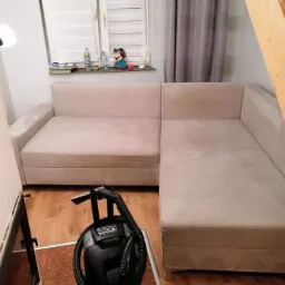 Beżowa kanapa narożna częściowo wyczyszczona z użyciem odkurzacza piorącego w domu w Wieprznicy, widoczne schody i okno z dekoracjami.