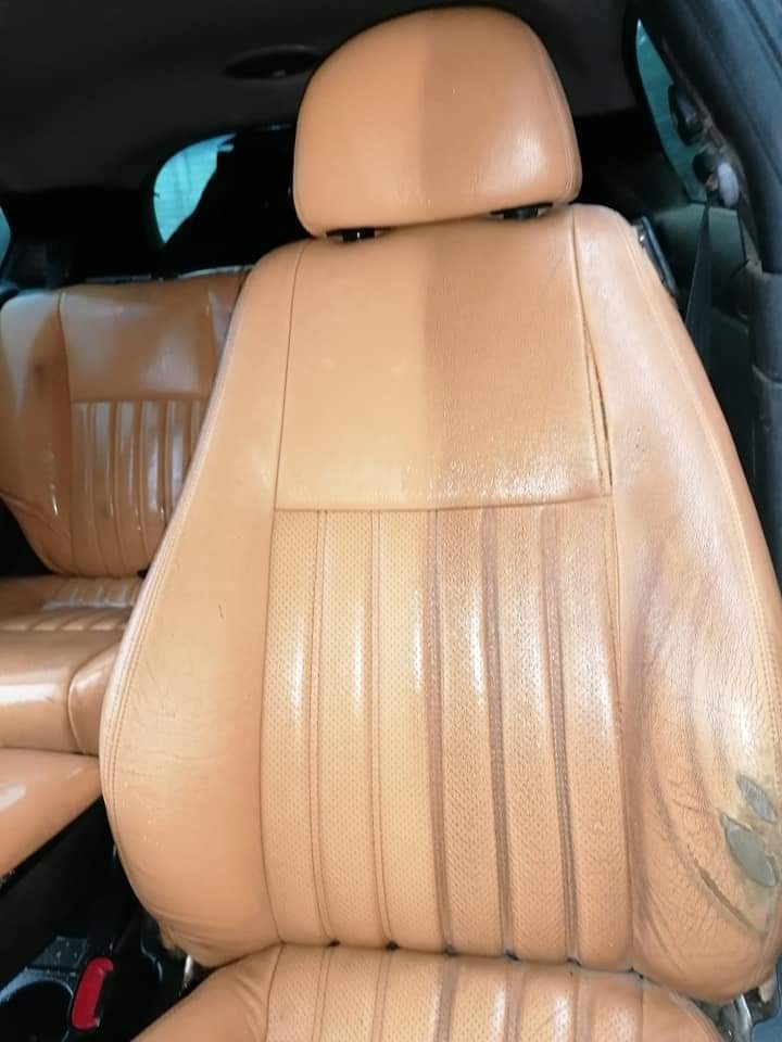 Fragment beżowego skórzanego fotela samochodowego, widoczna różnica w czystości po lewej stronie, z prawej strony widoczne ślady zużycia i zabrudzenia.