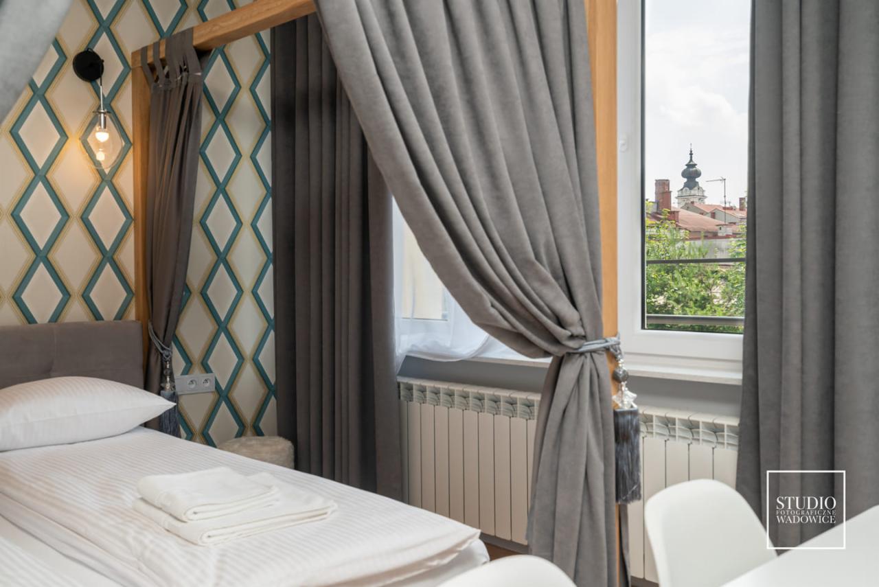 Eleganckie, szare zasłony z dekoracyjnymi wiązaniami w pokoju hotelowym z widokiem na miasto przez okno.