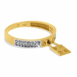 Złoty pierścionek z brylantami i zawieszką w kształcie kłódki, sfotografowany na białym tle we Wrześni.