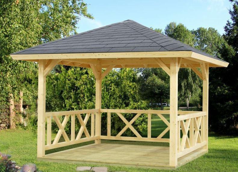 Nowa, drewniana altana z szarym, gontowym dachem, otoczona zielenią drzew i trawnikiem.