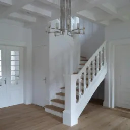 Jasne, minimalistyczne wnętrze: białe ściany, drewniana podłoga, białe schody z drewnianymi stopniami, nowoczesny, srebrny żyrandol i kasetonowy sufit.