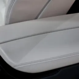 Jasna skórzana tapicerka samochodowa, widoczne szwy i przycisk 'AUTO H'.