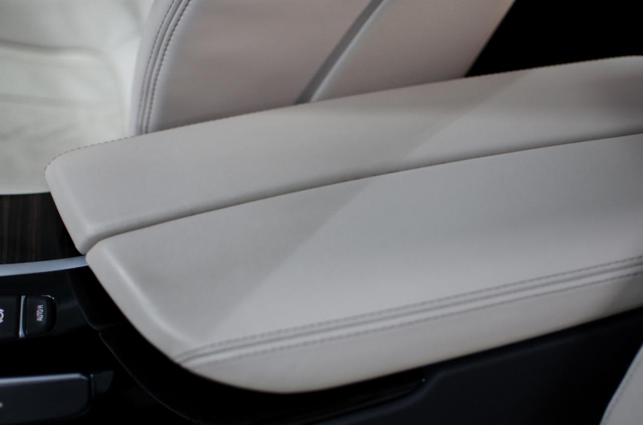 Jasna skórzana tapicerka samochodowa, widoczne szwy i przycisk 'AUTO H'.
