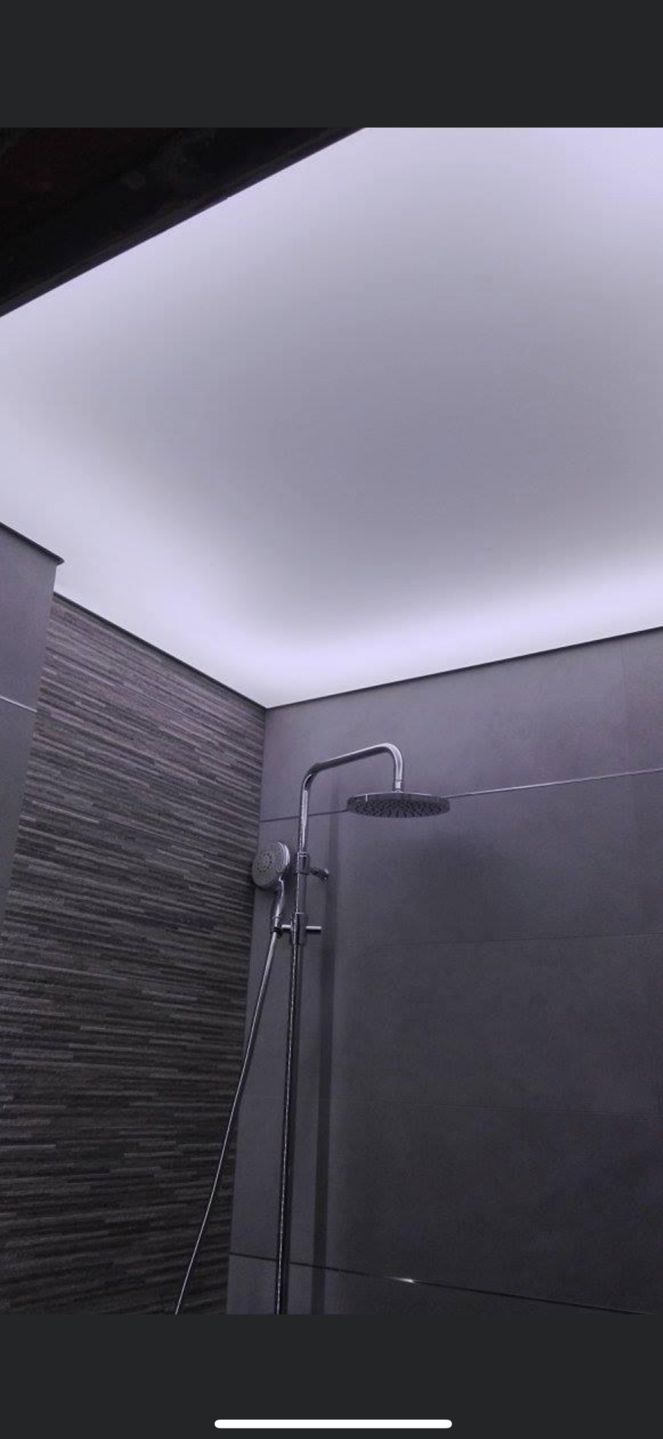 Nowoczesna łazienka z szarą mozaikową ścianą, deszczownicą i podświetlanym sufitem, ukazana z perspektywy żabiej