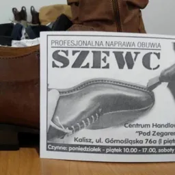 Brązowe skórzane półbuty męskie na tle ulotki reklamującej usługi szewskie, z informacją o adresie i godzinach otwarcia punktu naprawy obuwia.