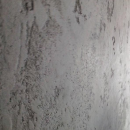 Cztery Kąty - Szara ściana z wyraźną, nieregularną fakturą, widoczny znak wodny w lewym górnym rogu.