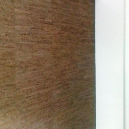 Cztery Kąty - Brązowa ściana z wyraźną fakturą, narożnik pomalowany na biało, widoczny włącznik światła i logo firmy 'Cztery Kąty' na górze ściany.