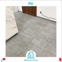 Wyczyszczona, jasnoszara wykładzina dywanowa w biurze po praniu, widoczny fragment białego biurka z marmurowym wzorem i brązowe drzwi z otworami wentylacyjnymi.