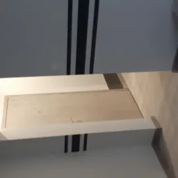 Wnętrze po odświeżeniu: białe ściany z czarnymi pasami dekoracyjnymi, jasne drewniane panele podłogowe, widoczny fragment zabudowy meblowej i narzędzia malarskie.