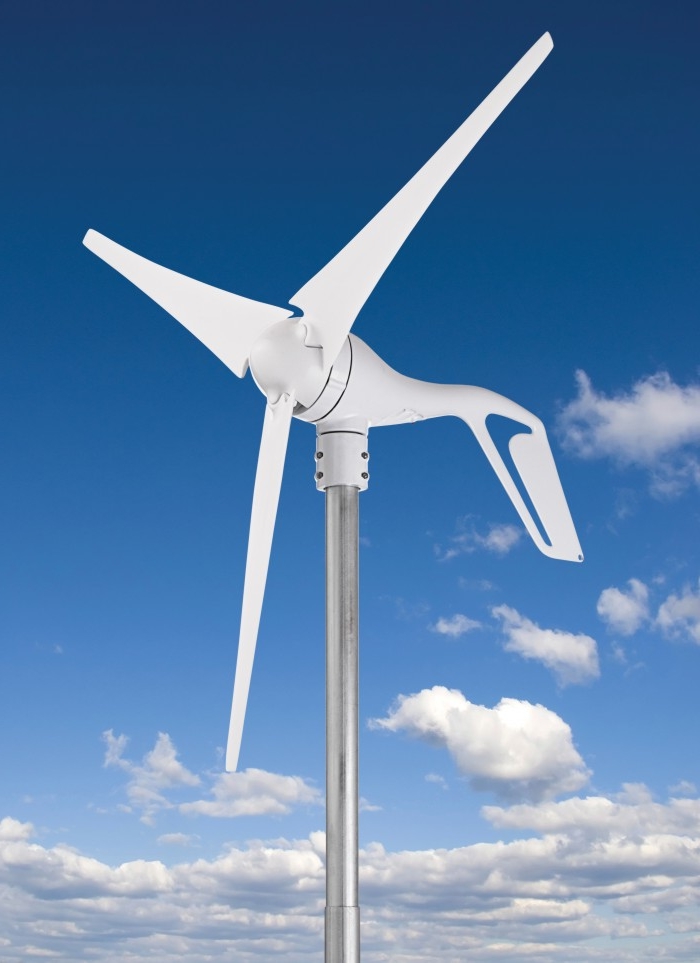 Niskoobrotowa turbina wiatrowa o trzech łopatach, zamontowana na metalowym maszcie, na tle błękitnego nieba z białymi obłokami.