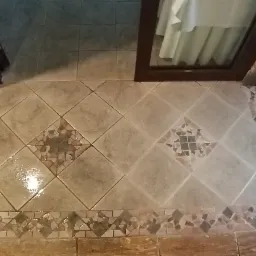 Kafelki podłogowe z wzorem rombów i mozaiką, widok z góry, po umyciu widoczne mokre plamy.