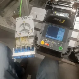 Przygotowanie światłowodów do spawania za pomocą spawarki światłowodowej Fujikura S178A ver. 2, widoczna kaseta światłowodowa z włóknami i niebieskimi złączami.