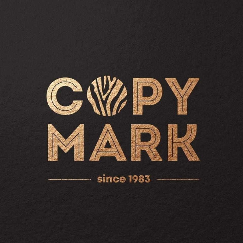 Złote logo 'COPY MARK' z rokiem założenia 1983 na czarnym, teksturowanym tle. Litera 'O' w 'COPY' zastąpiona abstrakcyjnym wzorem zebry.