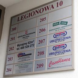 Inter-Gra Artur Szafran - Tablica informacyjna z nazwami i numerami lokali w budynku Legionowa 10, prezentująca różnorodne firmy, w tym kancelarię notarialną, agencję nieruchomości, kancelarię adwokacką, firmy...