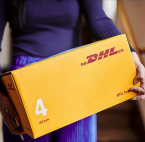 Osoba trzyma żółte pudełko DHL z widocznym logo i numerem 4, na tle schodów.