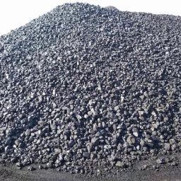 Ogromny pryzmat czarnego węgla kamiennego w składzie, z widoczną koparką w tle po lewej stronie.