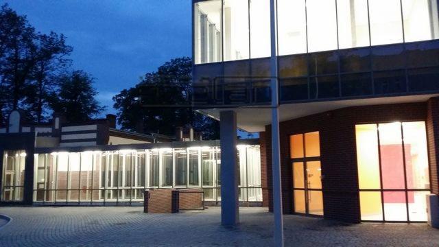 Nowoczesny budynek biurowy z przeszkloną fasadą i oświetleniem zewnętrznym, widoczny o zmierzchu.