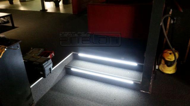 Podświetlane schody w obiekcie komercyjnym z widocznymi narzędziami i odkurzaczem w tle.