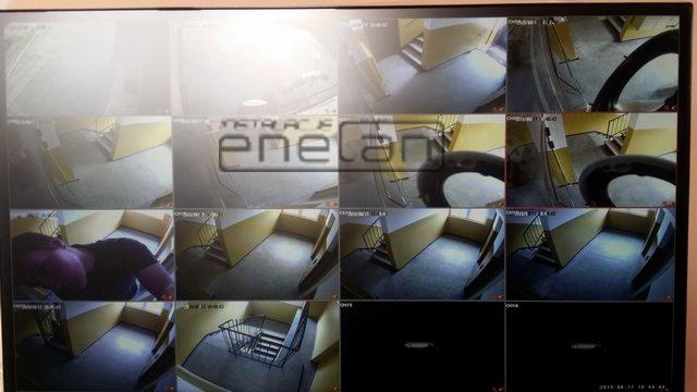 Ekran monitora z podglądem z kamer monitoringu na klatce schodowej, widoczne różne ujęcia i logo firmy nadrukowane na obrazie.