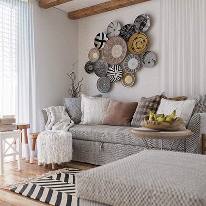 Jasny salon w stylu boho z szarą sofą, dekoracyjnymi talerzami na ścianie, pufem z frędzlami i drewnianymi belkami stropowymi.