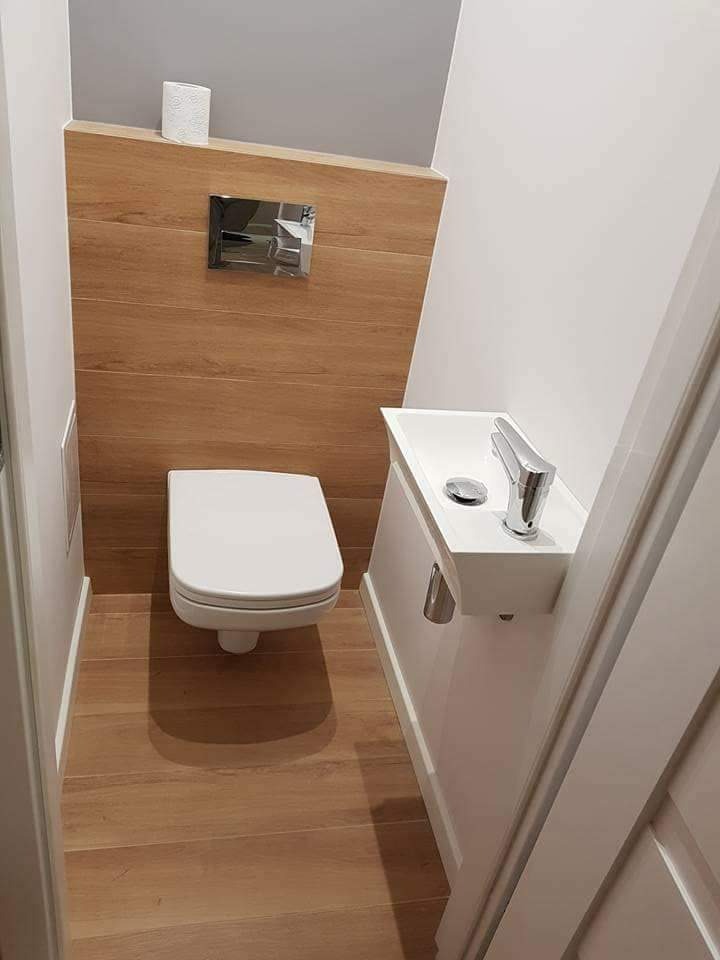 Nowoczesna, minimalistyczna toaleta w Czarnym Dunajcu z drewnopodobnymi panelami ściennymi i podłogą, podwieszana miska WC, umywalka nablatowa z chromowaną baterią oraz ukryta spłuczka.