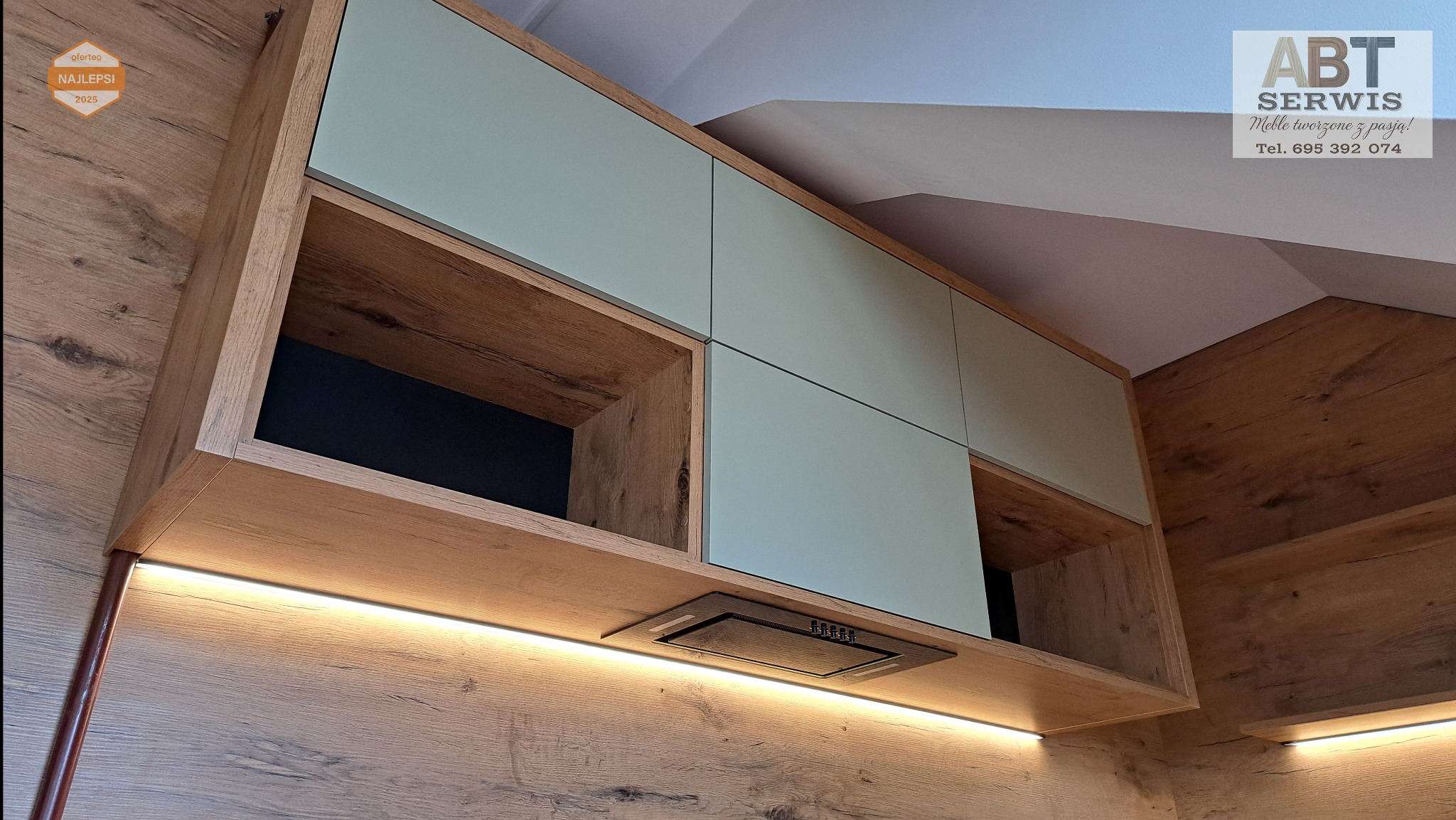 Drewniana zabudowa kuchenna z oświetleniem LED, jasnymi frontami i otwartymi półkami. Uwagę zwraca skośny sufit i nietypowe wykończenie.