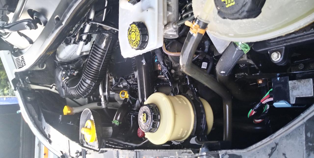 Wnętrze komory silnika samochodu, widoczne zbiorniki płynów eksploatacyjnych, przewody i elementy konstrukcyjne, po umyciu, z widocznymi kroplami wody.