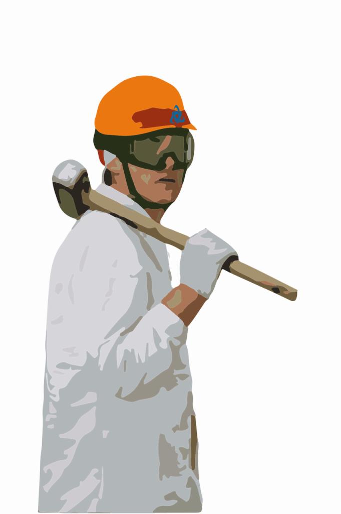 Mężczyzna w kasku i okularach ochronnych, ubrany w biały kombinezon, trzyma na ramieniu duży młot.