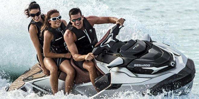 Trzy osoby w okularach przeciwsłonecznych i kamizelkach ratunkowych na skuterze wodnym Sea-Doo GTS 300, płynącym po wzburzonej wodzie.