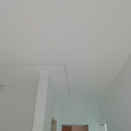 6th Avenue - Świeżo pomalowany sufit i ściany na biało, widoczne profile sufitowe i przygotowane miejsce na oświetlenie punktowe, fragment drzwi w tle.