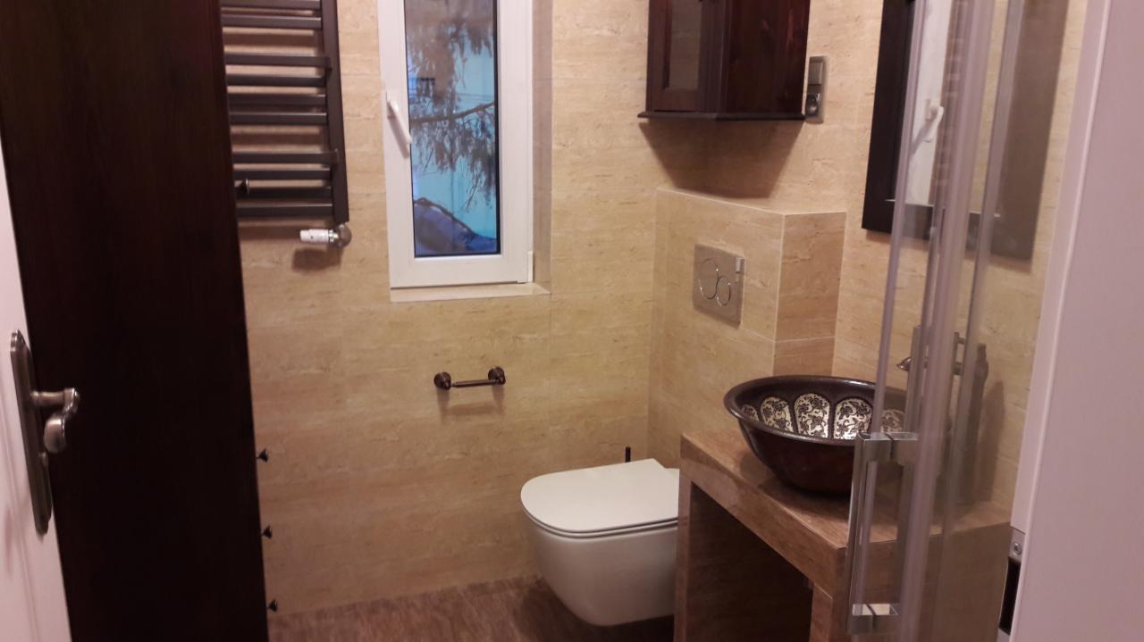 Beżowa łazienka z wiszącą toaletą, dekoracyjną umywalką w stylu orientalnym i brązowym grzejnikiem drabinkowym