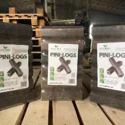 Trzy paczki brykietu drzewnego Pini-Logs, zapakowane w folię, z etykietami producenta Ecolinex, ustawione na drewnianej palecie w magazynie.