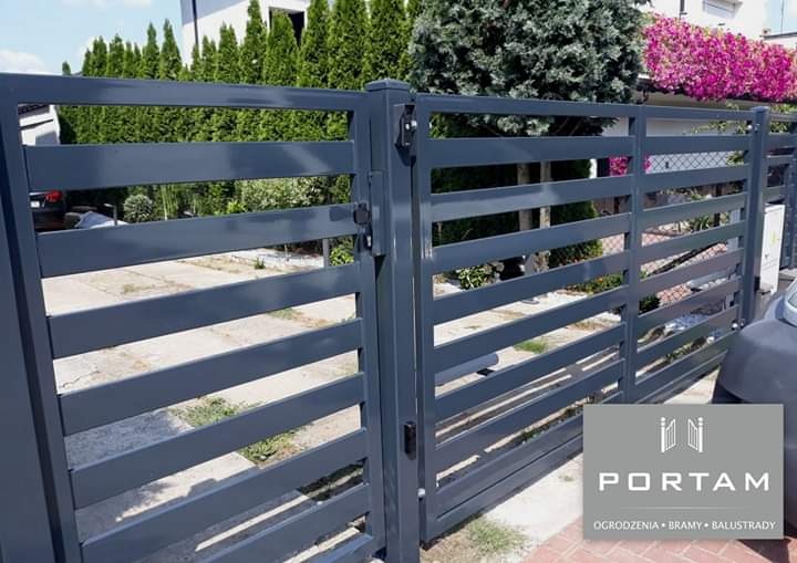 Nowoczesna, pozioma brama wjazdowa z metalu pomalowana na szaro, widok z zewnątrz posesji, z logo firmy w prawym dolnym rogu.